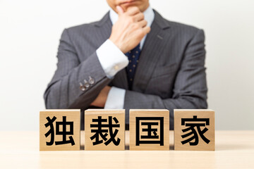 「独裁国家」と書かれたブロックとビジネスマン