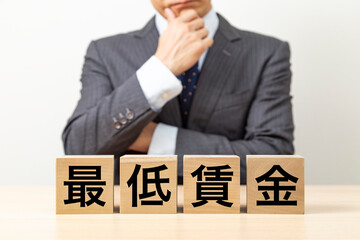 Obraz premium 「最低賃金」と書かれたブロックとビジネスマン