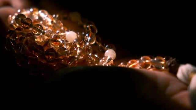 Woman's hands cupping collection of amber gemstones and beads