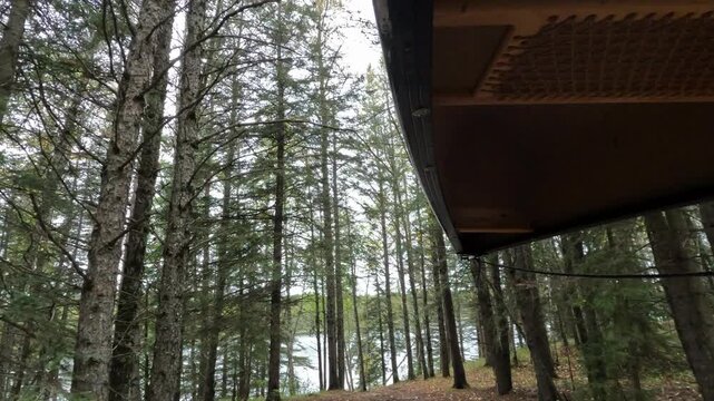 POV while carrying portaging a canoe through a forest towards a small lake