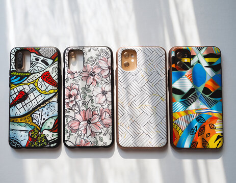 A vibrant display of diverse smartphone covers featuring unique artistic patterns-from bold abstract to delicate floral designs. - Powered by Adobe
