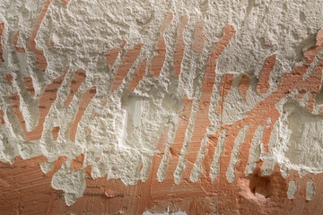 Rough texture of a wall with peeling plaster and traces of removed paint, abstract background with a natural chaos of lines and textures.