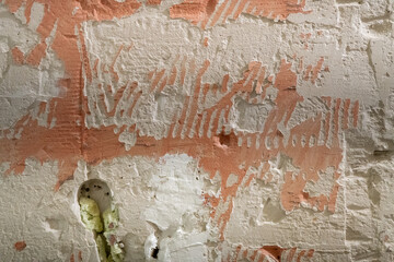 Rough texture of a wall with peeling plaster and traces of removed paint, abstract background with a natural chaos of lines and textures.