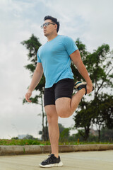 Man stretching quadriceps outdoors on a cloudy day during warm-up routine for outdoor fitness