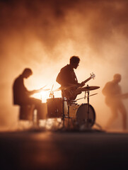 Obraz premium Silhouette of a band performing live on stage in smoky, golden light. Evokes energy, passion, and musical expression. Great for entertainment and event promotion.