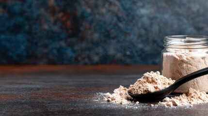 A rustic setting featuring whole wheat flour spilled from a wooden spoon beside a jar, on a textured dark surface, emphasizing natural ingredients and organic cooking.