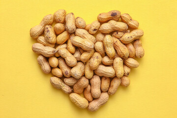 Heart shape made of peanuts on a bright yellow background, symbolizing love for healthy snacks. healthy eating and affection for nutritious foods.