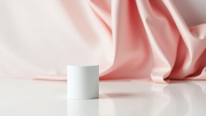 Minimalist product display with soft pink silk drapery and white cylinder pedestal