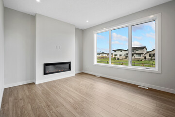 Large, empty living room with a fireplace and a window
