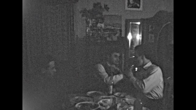 Funny man drinks strong alcohol with friends indoor. Male grimaces, makes faces after drinking vodka. Hilarious alcoholism. Men group toasting at home party. Old film. Archival retro. Vintage archive