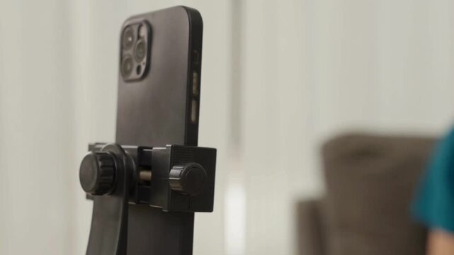 Close up of hands fixing a phone on a tripod for vertical recording in 4K, showing precise setup, stable framing, and modern content creation workflow.