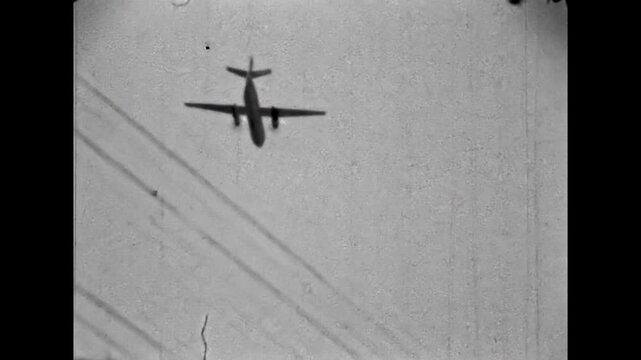 Military propeller airplane flying directly overhead against sky. Training takeoff of aircraft for transporting personnel, equipment from airfield. Old film. Archival retro 1960s. Vintage archive.
