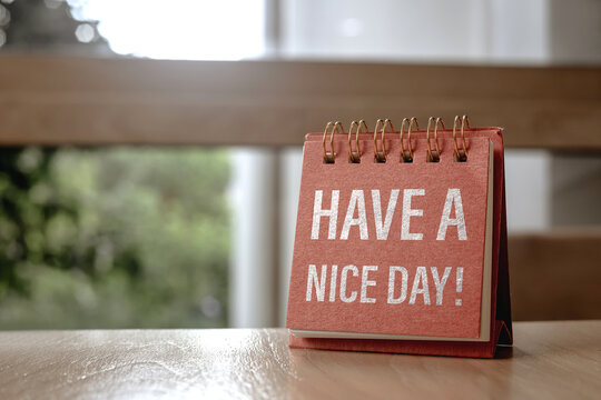A small calendar page displaying the message, Have a nice day on wooden table. Concept of inspiration and reminder for a good start to day, whether for living or working.