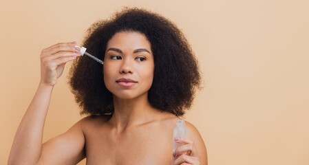 African American woman applying face serum with pipette