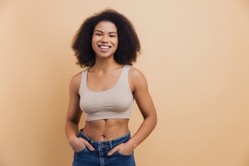 African American woman smiling wearing sports bra and jeans