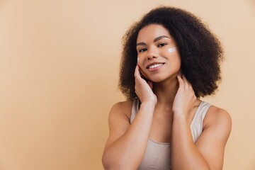African American woman applying face cream for skincare