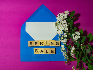 Spring sale! Blue envelope with a white sheet of paper for a message, a spiraea branch, on a pink background. Spring women's discount concept.
