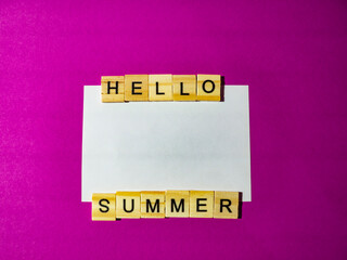 Wooden blocks spelling hello summer on pink background