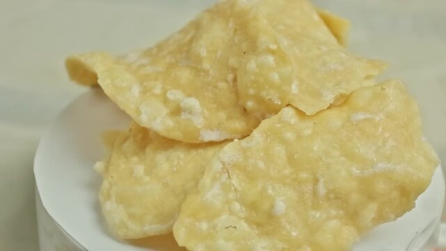 Stack of pale yellow sweet crackers with crunchy texture rotating on a white display