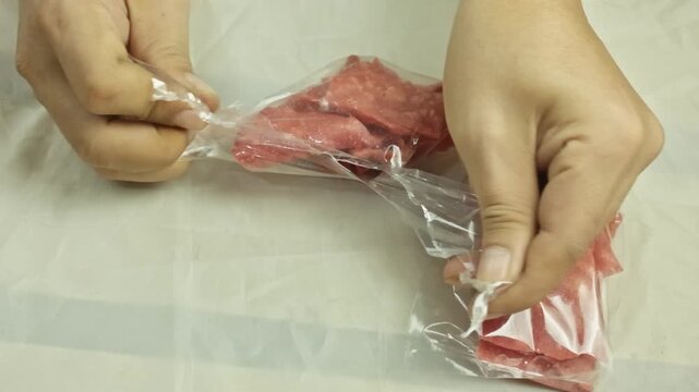 Hands removing crunchy pink sweet crackers from plastic packaging