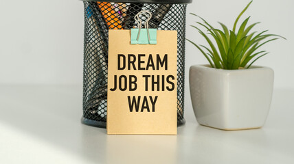 A small piece of paper with the words Dream Job this Way written on it. The paper is clipped to a metal container
