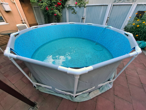 Outdoor open-air swimming frame pool. Water is pouring into pool