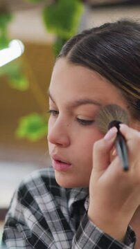 Teen model with makeup tools, Young female model practicing contouring techniques, Young female model under studio lights demonstrating makeup application and posing for editorial photography