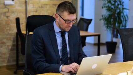 video. Caucasian businessman is sitting, working , looking around, seeing three sandwiches and...