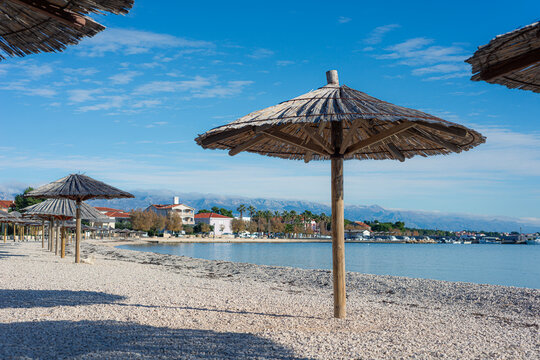 Parasols, shaders on a pebble beach on island of Vir, Croatia. Famous tourist destination.