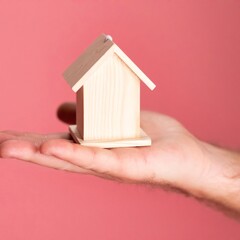 The image shows a house icon placed in someone's hand