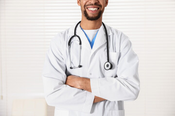 Fototapeta premium Smiling doctor in medical uniform with stethoscope in clinic, closeup