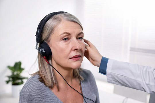 Hearing test. Doctor adjusting patient's audiometric headphones in clinic, closeup
