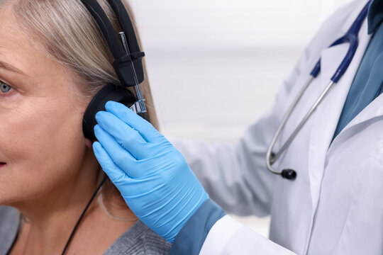 Hearing test. Doctor adjusting patient's audiometric headphones in clinic, closeup