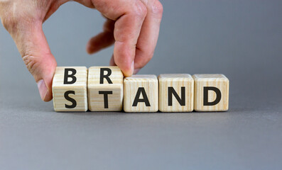 Brand or stand symbol. Concept words Brand Stand on beautiful wooden blocks. Beautiful grey background. Businessman's hand. Business brand or stand concept. Copy space.