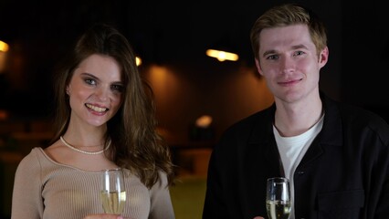 Happy young man and woman sitting in the restaurant and posing at camera while showing thumbs up. Lifestyle, relationship, date concept.