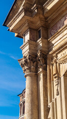 Decorations on a marble column against a blue sky background. Decorations on a corner column of a building. Marble architectural decorations