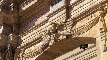 Head of a woman on a marble arch. Decorations on a marble arch close-up. Marble architectural decorations