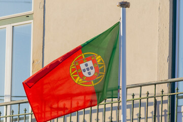 Portugal flag displaying its coat of arms on a flagpole