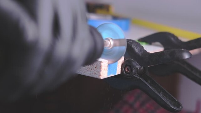 Handyman in protective gloves cutting a piece of chipboard with a power tool in a workshop