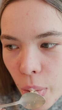 teen caucasian girl licking spoonful cream while evaluating flavor, expressive closeup of tongue and lips with subtle contemplation, home tasting session with foodie and critic vibes, texture testing