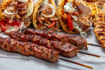 Gyro sliced meat pita bread wraps, pork souvlaki skewers, traditional street food, closeup