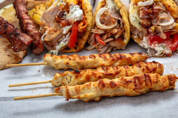 Gyro sliced meat pita bread wraps, chicken souvlaki skewers, traditional street food, closeup