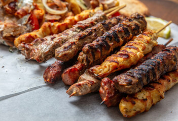 Mixed grilled meat platter, meat skewers, kebab pieces, and blur gyro wraps background, closeup
