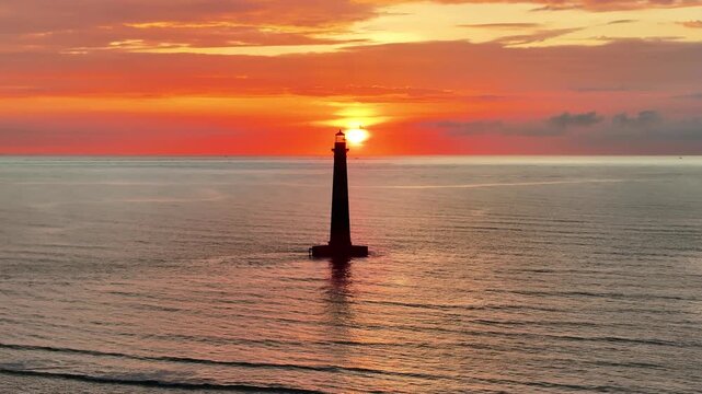 Sunrise Over the Ocean With a Morris Island Lighthouse Standing Tall Against the Sky Near the Water in Folly Beach, South Carolina coast