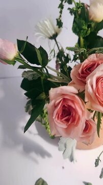 A delicate arrangement of blush pink roses paired with fresh greenery in a warm clay vase, softly lit to highlight natural textures, petals, and organic shapes.