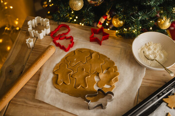 Holiday background. Uncooked raw Christmas gingerbread cookies with cookie cutters on a table, top...