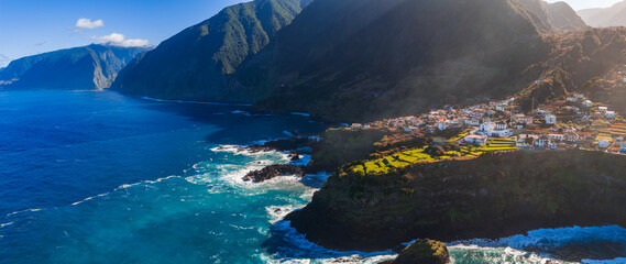 Late afternoon light casts warm tones on a cliff lined Atlantic coast, waves hit dark volcanic...