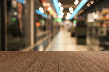 Empty wooden table against blurred view of shopping mall. Space for design