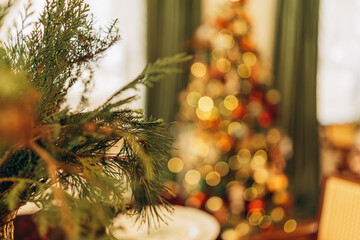 Festive Christmas decorations with blurred tree and greenery in cozy interior
