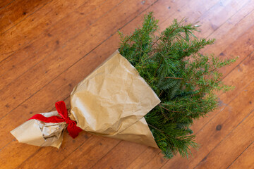 Christmas greenery bouquet with red ribbon on wooden floor
